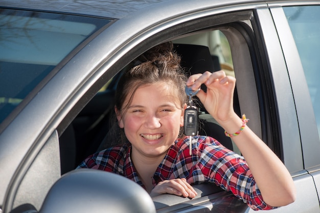 Jonge tiener meisje, zittend in de auto, sleutels weergeven