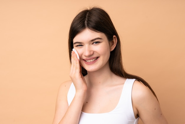 Jonge tiener met wattenschijfje voor het verwijderen van make-up uit haar gezicht
