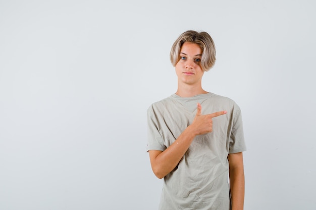 Foto jonge tienerjongen die recht in een t-shirt wijst en er zelfverzekerd uitziet. vooraanzicht.