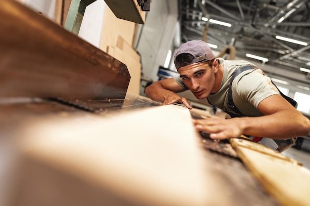 Foto jonge timmerman bezig met houtbewerkingsmachines in de meubelfabriek