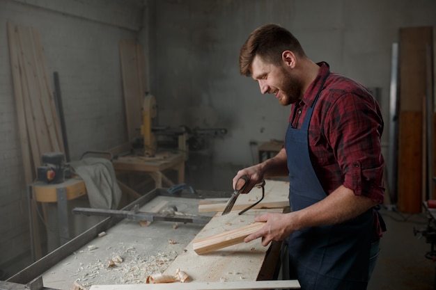 Jonge timmerman met een schort in zijn atelier