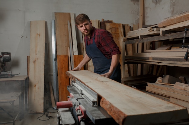 Jonge timmerman met een schort in zijn atelier