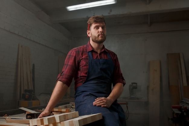 Jonge timmerman met een schort in zijn atelier