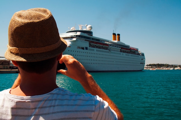 Foto jonge toerist met hoed schieten een cruiseschip