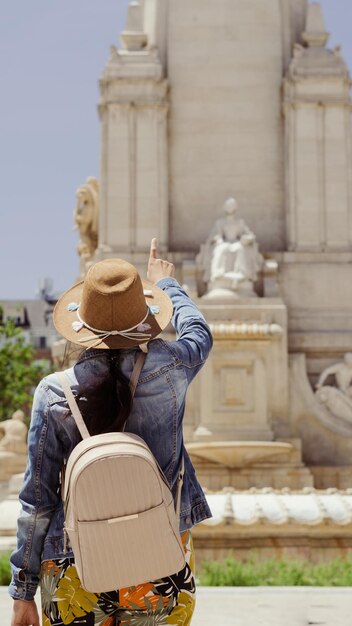 Foto jonge toeriste vrouw voor een standbeeld op een plein in madrid