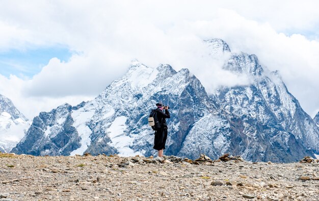 Jonge toeristen in jassen maken foto's van besneeuwde rotsen vanaf de top van de berg