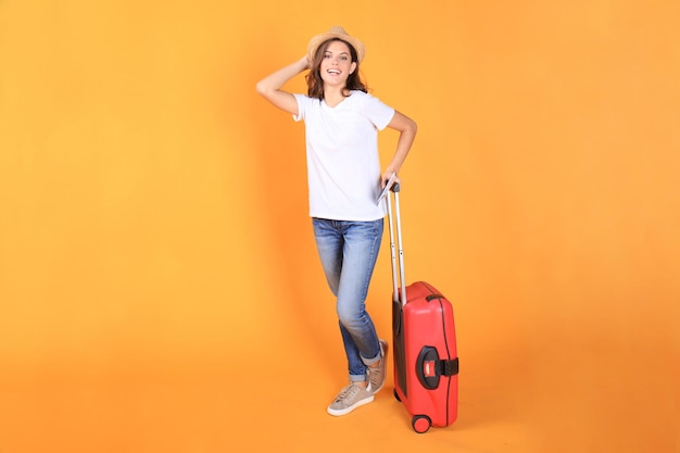 Jonge toeristische meisje in zomer casual kleding, met rode koffer, paspoort, tickets geïsoleerd op beige achtergrond