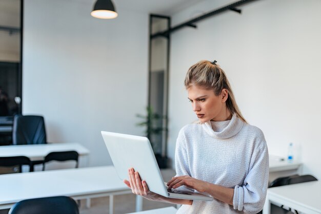 Jonge toevallige onderneemster die laptop binnen met behulp van.