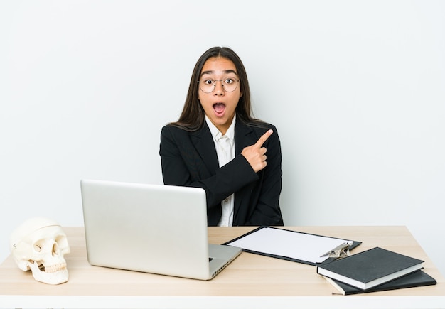 Jonge traumatoloog Aziatische vrouw die op witte muur wordt geïsoleerd die naar de kant richt