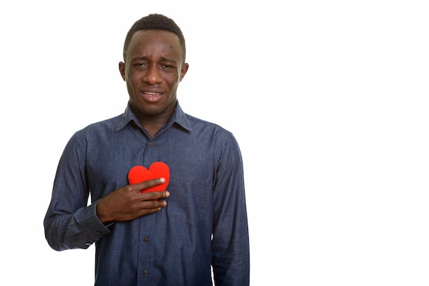 Jonge triest Afrikaanse man met rood hart op de borst