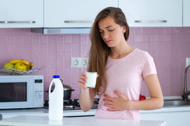 Jonge trieste ongelukkige vrouw die lijdt aan melkallergie en lactose-intolerantie