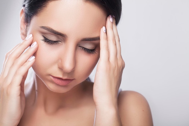 Jonge trieste vrouw raakt het voorhoofd aan en voelt sterke hoofdpijn