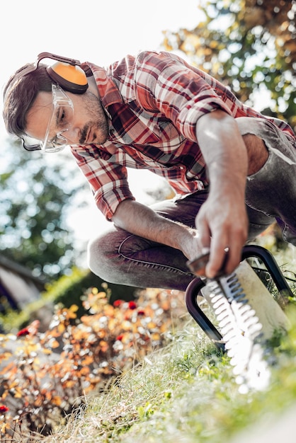 Jonge tuinman met professioneel tuingereedschap op het werk