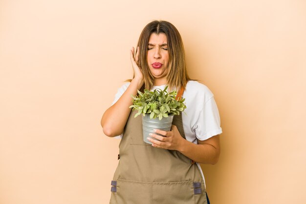 Jonge tuinmanvrouw die een geïsoleerde plant houdt die oren behandelt met handen