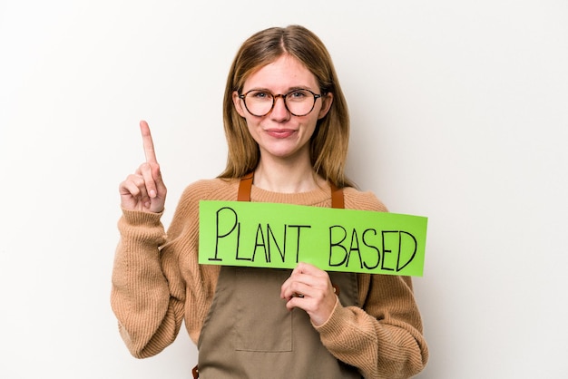 Foto jonge tuinmanvrouw die een op plan gebaseerd plakkaat houdt dat op witte achtergrond wordt geïsoleerd die nummer één met vinger toont