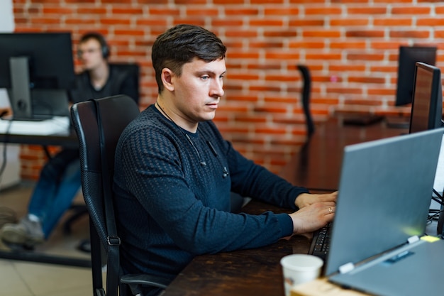 Jonge uitvoerende zitting bij zijn bureau met laptop die een document leest.