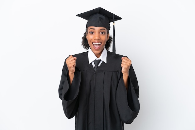 Jonge universitair afgestudeerde Afro-Amerikaanse vrouw geïsoleerd op een witte achtergrond die een overwinning viert in winnaarspositie