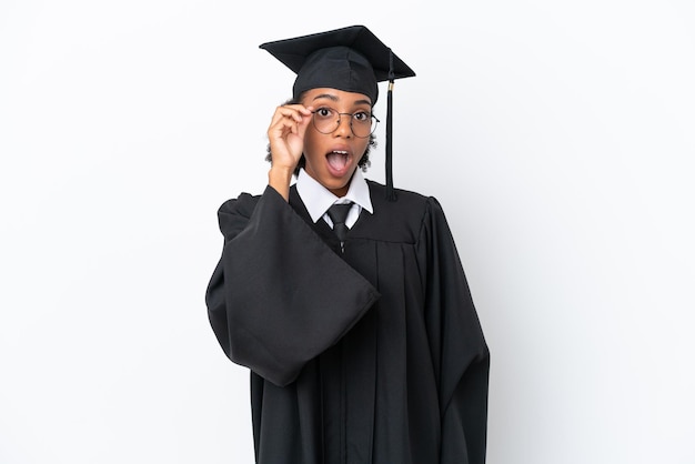 Jonge universitair afgestudeerde Afro-Amerikaanse vrouw geïsoleerd op een witte achtergrond met een bril en verrast