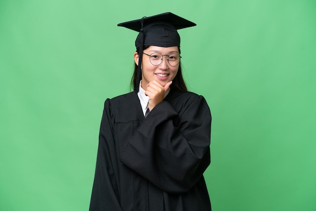 Jonge universitair afgestudeerde Aziatische vrouw over geïsoleerde achtergrond met een bril en glimlachen