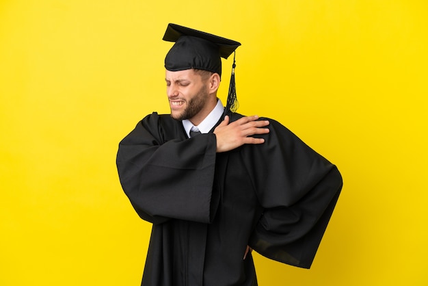 Jonge, universitair afgestudeerde blanke man geïsoleerd op een gele achtergrond die lijdt aan pijn in de schouder omdat hij moeite heeft gedaan