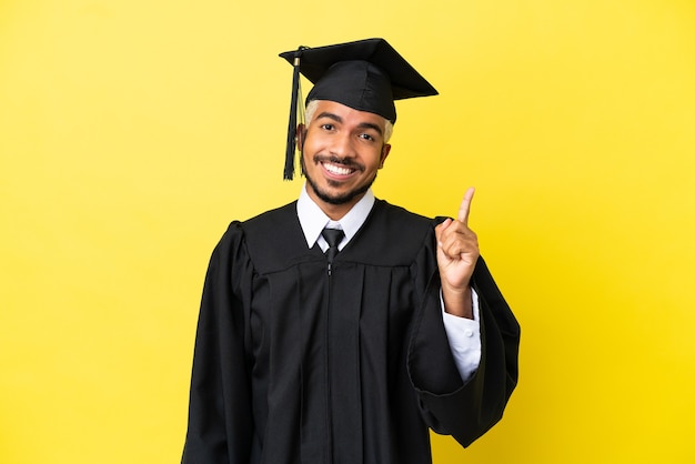 Jonge, universitair afgestudeerde Colombiaanse man geïsoleerd op een gele achtergrond die een vinger toont en opheft in teken van de beste