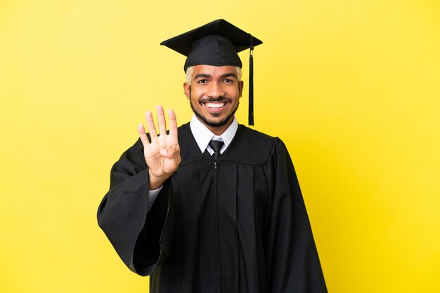 Jonge, universitair afgestudeerde Colombiaanse man geïsoleerd op gele achtergrond gelukkig en vier tellen met vingers