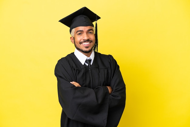 Jonge, universitair afgestudeerde Colombiaanse man geïsoleerd op gele achtergrond met gekruiste armen en vooruitkijkend