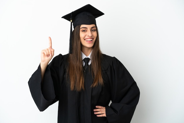 Jonge universitair afgestudeerde geïsoleerd op een witte achtergrond die een vinger toont en optilt in teken van de beste