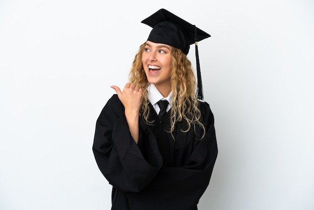 Jonge universitair afgestudeerde geïsoleerd op een witte achtergrond die naar de zijkant wijst om een product te presenteren