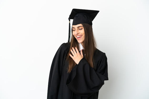 Jonge universitair afgestudeerde geïsoleerd op een witte achtergrond terwijl hij glimlacht