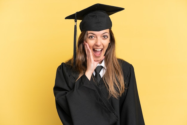 Jonge universitair afgestudeerde geïsoleerd op gele achtergrond met verrassing en geschokte gezichtsuitdrukking