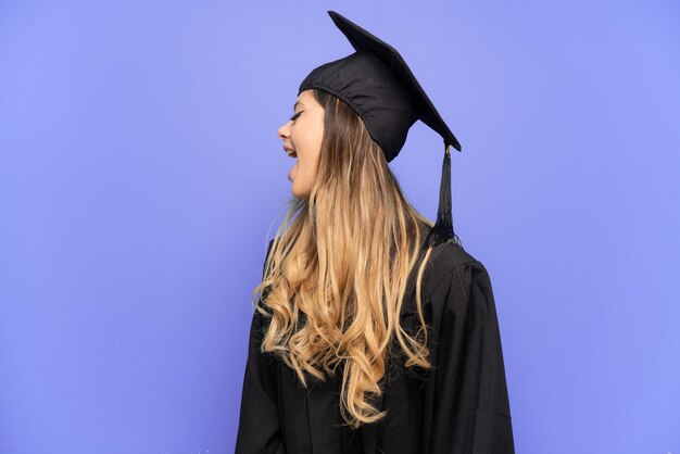 Jonge universitair afgestudeerde Russisch meisje geïsoleerd op een witte achtergrond lachen in laterale positie