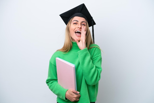 Jonge universitair afgestudeerde vrouw geïsoleerd op een witte achtergrond schreeuwen met wijd open mond