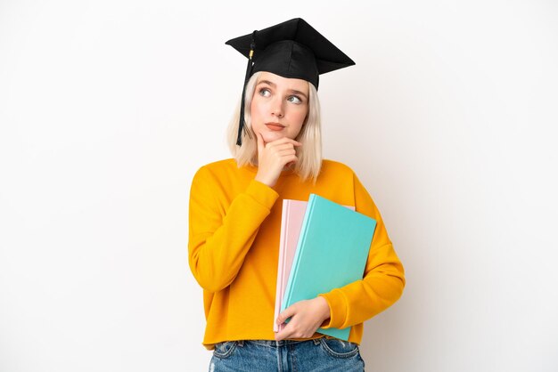 Jonge universitaire blanke vrouw afgestudeerd geïsoleerd op een witte achtergrond met twijfels