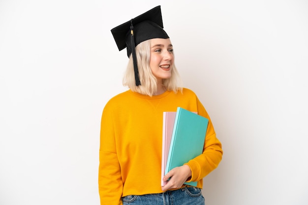 Jonge universitaire blanke vrouw afgestudeerd geïsoleerd op een witte achtergrond op zoek naar kant