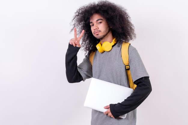 Jonge universiteitsjongen met afrohaar op witte achtergrond met een computer op zijn arm