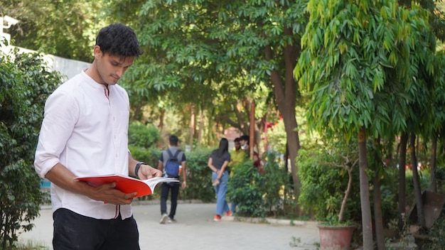 Jonge universiteitsjongen met boek op universiteitscampus