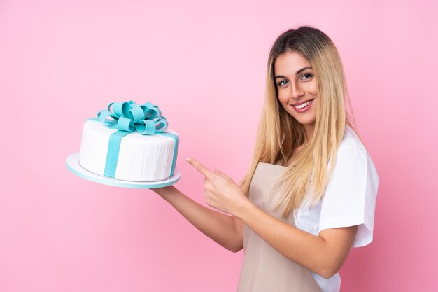 Jonge Uruguayaanse gebakjevrouw met een grote cake en het richten