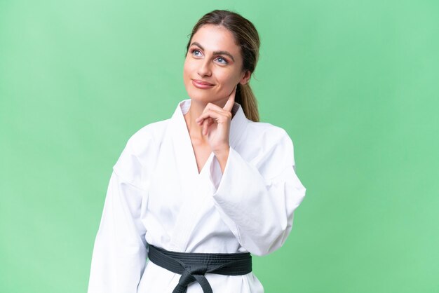 Jonge Uruguayaanse vrouw die karate doet over geïsoleerde achtergrond die een idee denkt terwijl ze omhoog kijkt