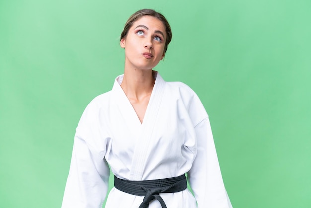 Jonge Uruguayaanse vrouw die karate over geïsoleerde achtergrond doet en omhoog kijkt