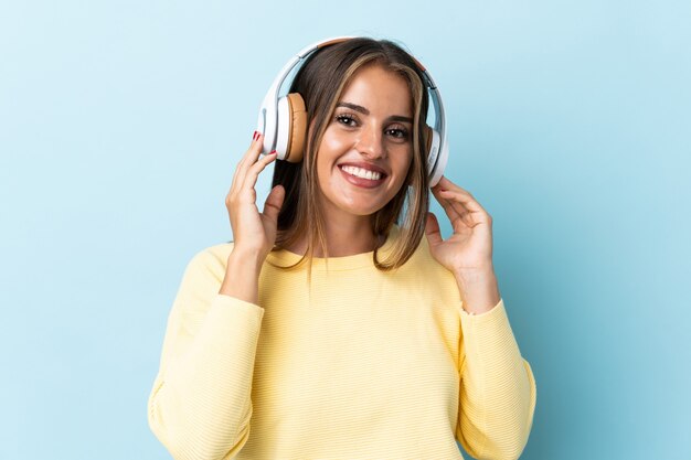 Jonge Uruguayaanse vrouw geïsoleerd op blauw luisteren muziek