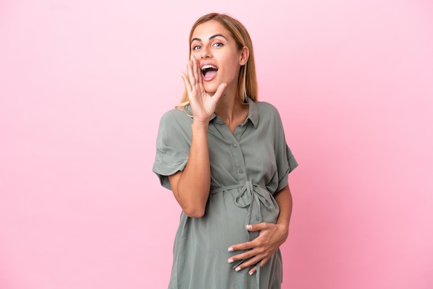 Jonge Uruguayaanse vrouw geïsoleerd op blauwe achtergrond zwanger en schreeuwen
