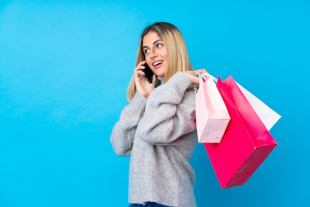 Jonge Uruguayaanse vrouw met boodschappentassen en een vriend bellen met haar mobiele telefoon