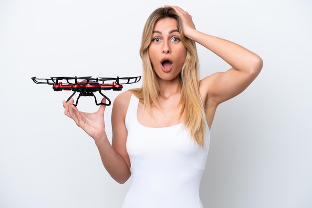 Jonge Uruguayaanse vrouw met een drone geïsoleerd op een witte achtergrond met verrassingsuitdrukking