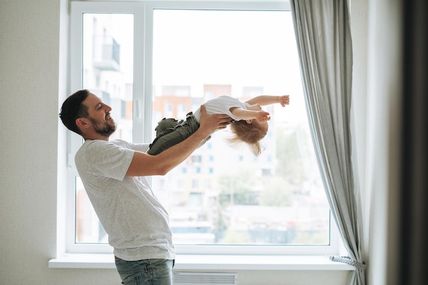 Jonge vader die plezier heeft met een baby in de buurt van het raam thuis