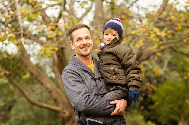 Jonge vader die zijn kleine zoon in park opheft