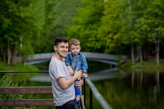 Jonge vader en zijn lachende zoon in het park, knuffelen en genieten van tijd samen, de viering van de dag van vaders.