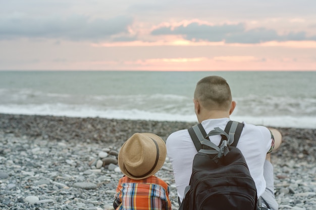 Jonge vader en zoon zitten op het strand