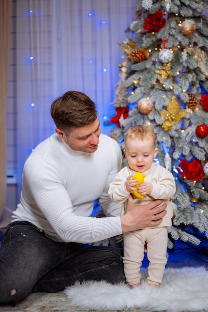 Jonge vader houdt zijn kleine zoon in zijn armen bij de kerstboom