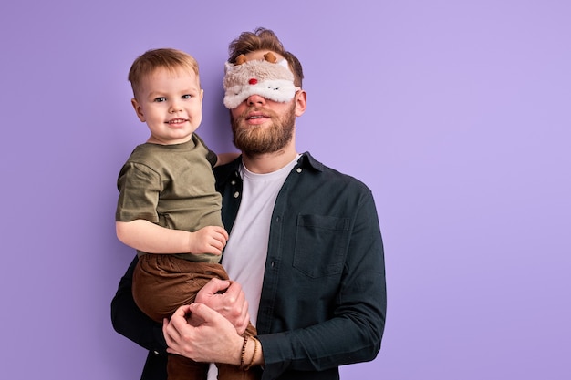 Jonge vader in slaapmasker wil het kind 's ochtends niet naar de kleuterschool brengen